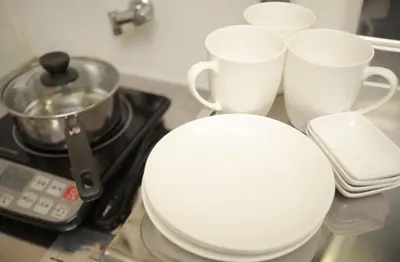 a white toilet sitting next to three cups on a stove at YK building in Tokyo