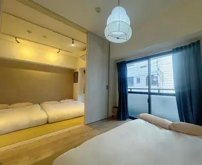 a bedroom with two beds and a large window at 浅草寺3分 浅草駅6分 2寝室+リビング2-6人 スカイツリービュー 駅近 成田空港&羽田空港直通 in Tokyo