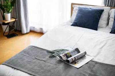 a white bed with a blue pillow and a book at DeLCCS\u543e\u59bb\u6a4bIII in Tokyo