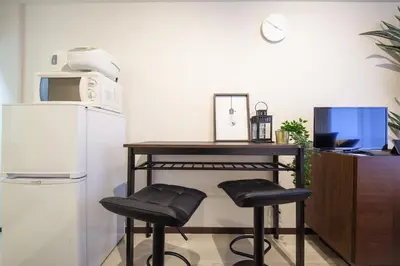 a kitchen with a table and two stools next to a refrigerator at \u30b7\u30a7\u30e2\u30ef\u30ed\u30ef\u30a4\u30e4\u30eb in Tokyo