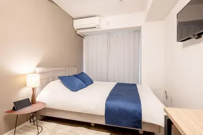 a bedroom with a bed with blue pillows and a table at Grande\u68ee\u4e0b in Tokyo