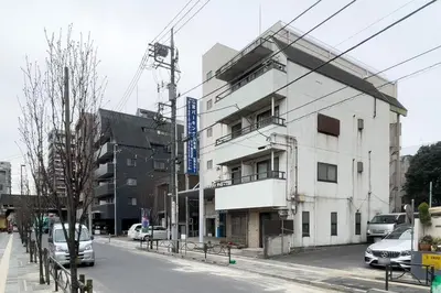 a white building on a street with cars parked in front at \u690d\u7530\u30cf\u30a4\u30c4 in Tokyo
