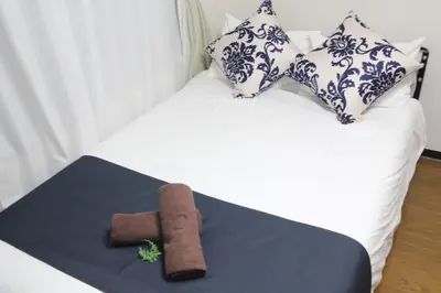 a bed with two pillows and a brown towel on it at LUANA NOGATA in Tokyo