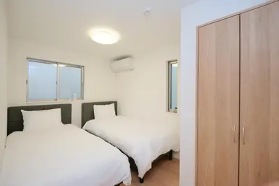 a bedroom with two beds and a wooden cabinet at Seirai Vacation Rental Hatsudai - Vacation STAY 15951v in Tokyo