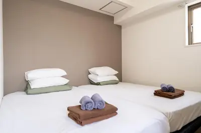 two beds with towels on top of them in a room at Nishinippori Guest House -Sendagi house- , elevator , private kitchen , private bathroom in Tokyo