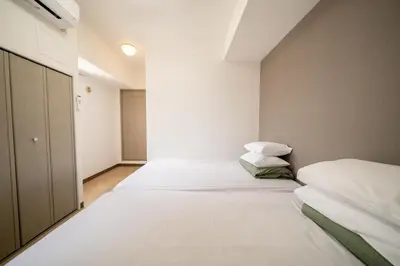 two beds in a room with white sheets and pillows at Nishinippori Guest House -Sendagi house- , elevator , private kitchen , private bathroom in Tokyo