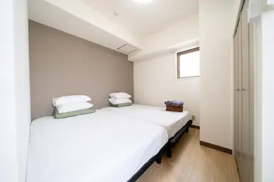 two beds in a room with white walls and a window at Nishinippori Guest House -Sendagi house- , elevator , private kitchen , private bathroom in Tokyo