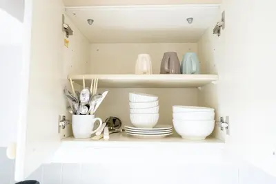 a cupboard with plates and bowls and utensils at Nishinippori Guest House -Sendagi house- , elevator , private kitchen , private bathroom in Tokyo
