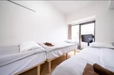 two beds in a room with a window and a tv at Nishinippori Guest House -Sendagi house- , elevator , private kitchen , private bathroom in Tokyo