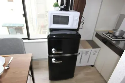 a microwave on top of a refrigerator in a kitchen at LUANA ARAI in Tokyo