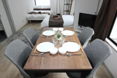 a wooden table with chairs and white plates and glasses at LUANA ARAI in Tokyo