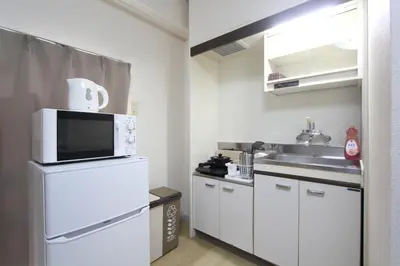 a small kitchen with a white refrigerator and a microwave at LUANA ARAI in Tokyo