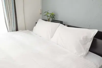 a white bed with white pillows in a bedroom at \u6e0b\u8c37\u99c5\u5f92\u6b696\u5206!\u9ad8\u901f\u30a4\u30f3\u30bf\u30fc\u30cd\u30c3\u30c8\u5149\u56de\u7dda in Tokyo