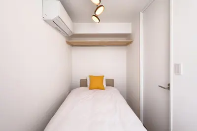 a small room with a bed with a yellow pillow at \u30c8\u30ea\u30a2\u30b9540 in Tokyo