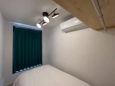 a bedroom with a window with a green curtain at \u30c8\u30ea\u30a2\u30b9540 in Tokyo