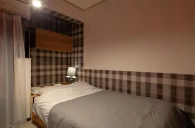 a bedroom with a bed with a plaid wall at \u30b5\u30f3\u30d1\u30ec\u30b9\u897f\u65b0\u5bbf in Tokyo