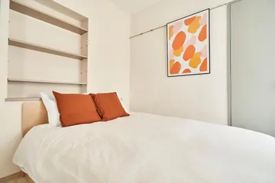 a bedroom with a white bed with an orange pillow at \u30a6\u30a3\u30f3\u30d9\u30eb\u30c7\u30e5\u30a8\u30c3\u30c8\u6075\u6bd4\u5bff\u7b2c5 in Tokyo