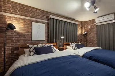 a bedroom with two beds and a brick wall at Nsk\u30d3\u30eb in Tokyo