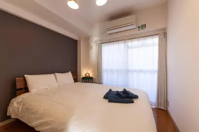 a bedroom with a large white bed with a window at \u30b7\u30e3\u30c8\u30ec\u897f\u5927\u4e95 in Tokyo