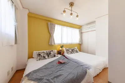 two beds in a small room with yellow walls at \u30d2\u30eb\u30ba\u99d2\u8fbc in Tokyo
