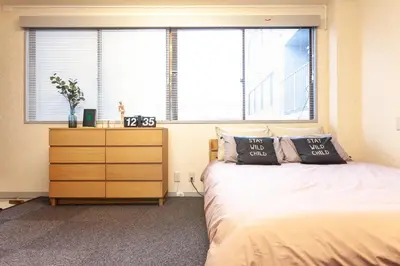a bedroom with a bed and a dresser and two windows at \u7b2c\u4e09\u5929\u53f0\u30d3\u30eb in Tokyo