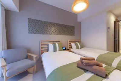 a bedroom with two beds and a chair and a lamp at Tokyo Sunshine Tower in Tokyo