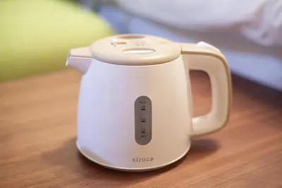 a white electric kettle sitting on a wooden table at \u690e\u540d\u753a\u30cf\u30a6\u30b9 in Tokyo