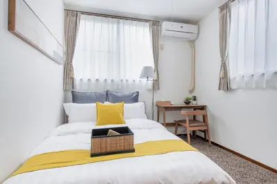 a bedroom with a bed with a yellow and white blanket at \u5e61\u30f6\u8c373\u4e01\u76ee\u6238\u5efa in Tokyo