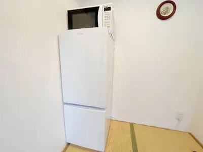 a white refrigerator in a room with a clock on the wall at \u82b1\u4e43\u90f7 \u8d64\u7fbd in Tokyo
