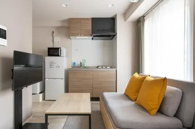a living room with a couch and a kitchen at Lafesta\u6771\u99d2\u5f62 in Tokyo