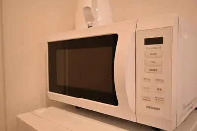 a white microwave oven sitting on top of a counter at \u6771\u99d2\u5f62102 in Tokyo