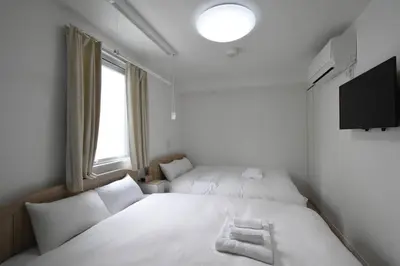 a bedroom with two beds and a tv and a window at \u6771\u99d2\u5f62102 in Tokyo