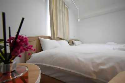 a bedroom with a bed and a table with a vase of flowers at \u6771\u99d2\u5f62102 in Tokyo