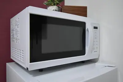 a microwave oven sitting on top of a white shelf at \u6771\u99d2\u5f62103 in Tokyo
