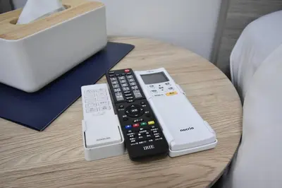 three remote controls sitting on a table next to a bed at \u6771\u99d2\u5f62201 in Tokyo