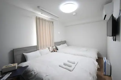 a bedroom with two white beds and a window at \u6771\u99d2\u5f62202 in Tokyo