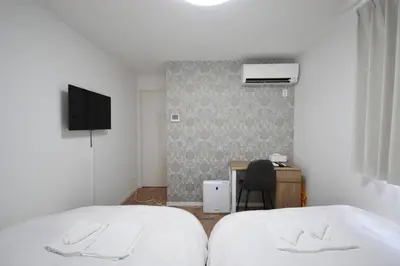 a bedroom with two beds and a desk and a television at \u6771\u99d2\u5f62203 in Tokyo