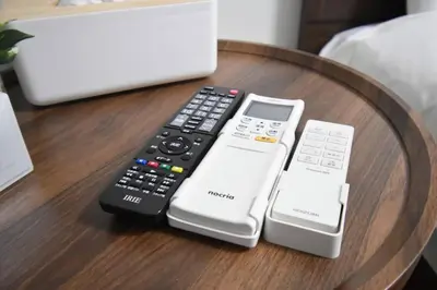 four remote controls sitting on a wooden table at \u6771\u99d2\u5f62302 in Tokyo