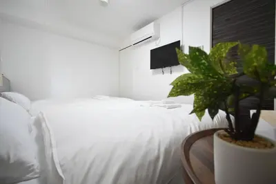 a bedroom with a white bed and a potted plant at \u6771\u99d2\u5f62402 in Tokyo