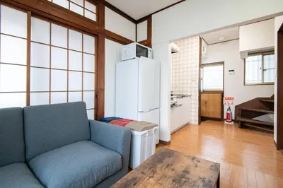 a living room with a couch and a refrigerator at Rea\u6771\u5411\u5cf64\u4e01\u76ee in Tokyo