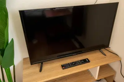 a flat screen tv sitting on a stand with a remote control at Rea\u6771\u5411\u5cf64\u4e01\u76ee in Tokyo