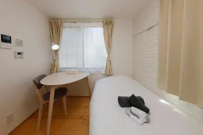 a small bedroom with a bed and a table at Nakano Five by Tranova in Tokyo