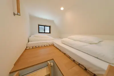 two beds in a small room with a window at Nakano Five by Tranova in Tokyo