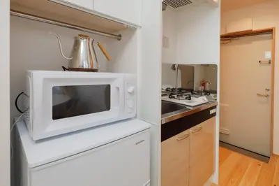 a kitchen with a microwave on top of a counter at Nakano Five by Tranova in Tokyo