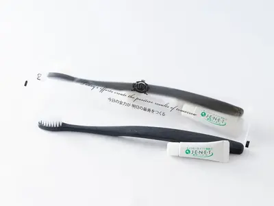 a toothbrush and a toothpaste tube on a white background at APA Hotel Hatchobori Ekimae in Tokyo