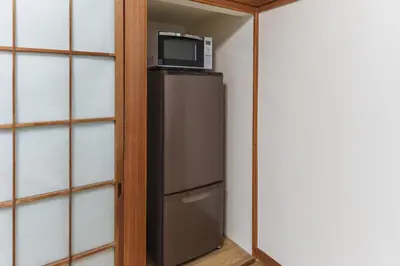 a microwave on top of a refrigerator in a closet at Hidden Valley in Tokyo