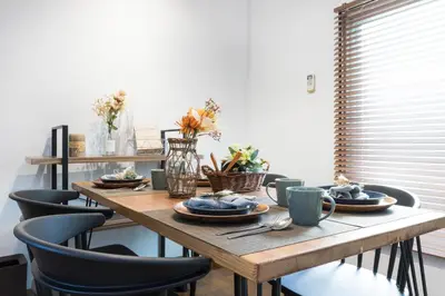 a wooden table with plates and cups and chairs at Takamatsu Guest House in Tokyo
