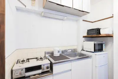 a white kitchen with a sink and a stove at Takamatsu Guest House in Tokyo