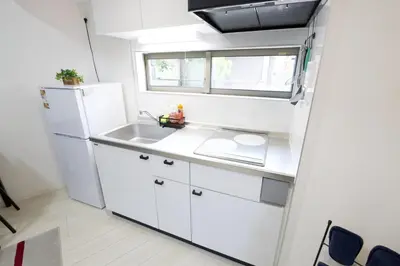 a white kitchen with a sink and a refrigerator at Aries Nishi-Shinjuku 302 in Tokyo