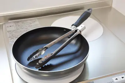 a frying pan with two utensils on top of a stove at Aries Nishi-Shinjuku 302 in Tokyo